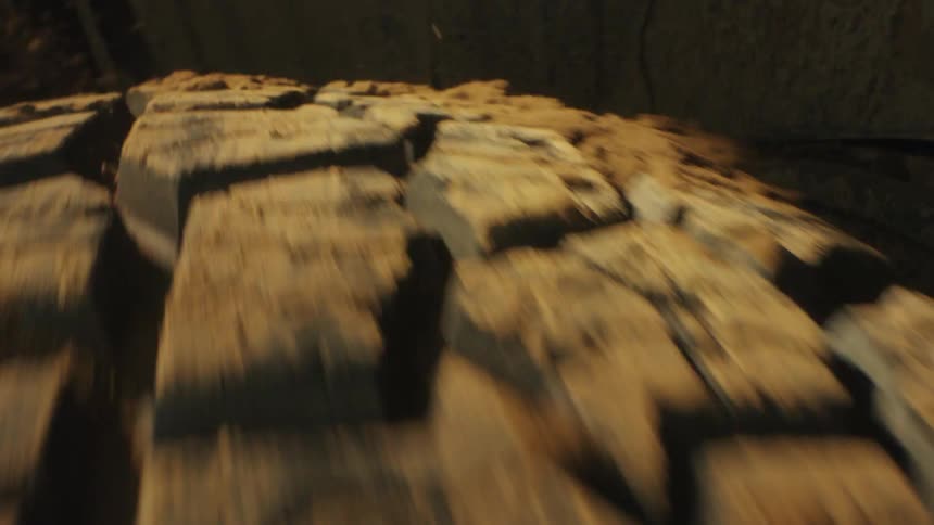 Vehicle wheel spins while dirt is thrown backward on uneven ground