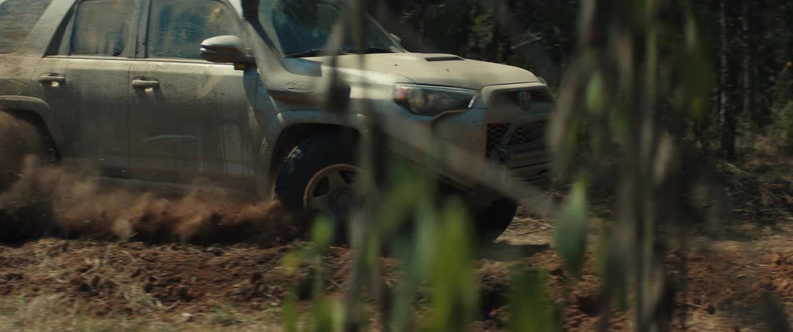 An offroad suv driving through the sandy forest at midday
