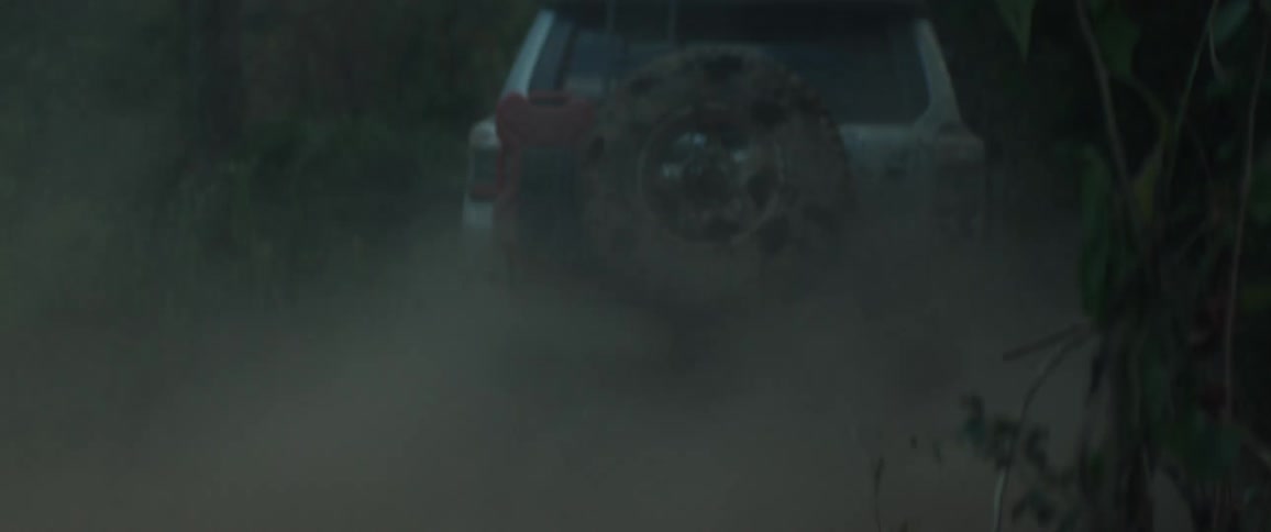 Pickup truck making a turn and kicking up mud through the forest