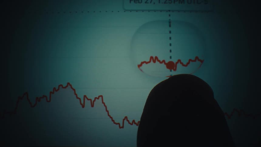 Finger points to a highlighted point on a line graph showing variations in financial values