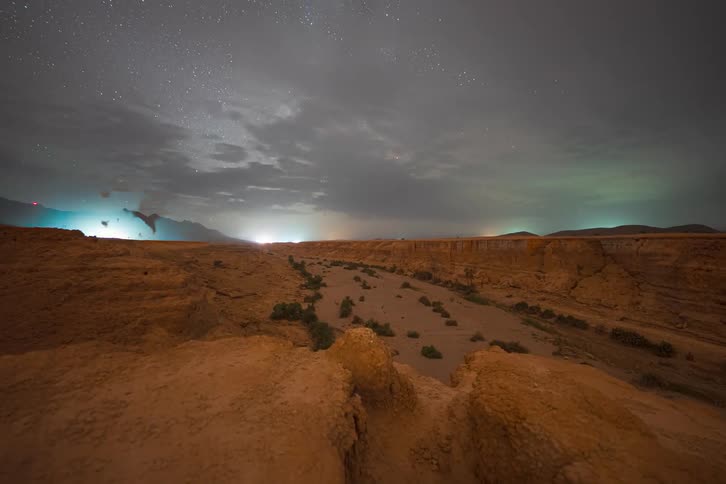 Starry sky with the milky way band over a rocky valley in a desert region at night
