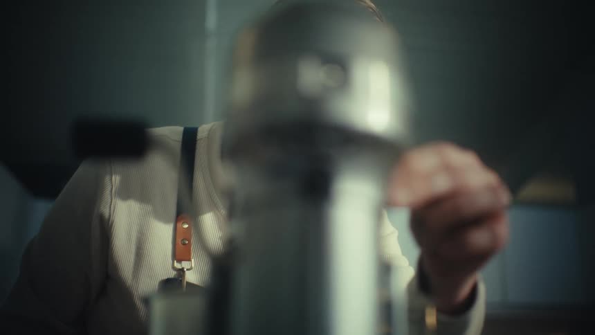 Man wearing glasses and apron watches a kitchen stand mixer during recipe preparation