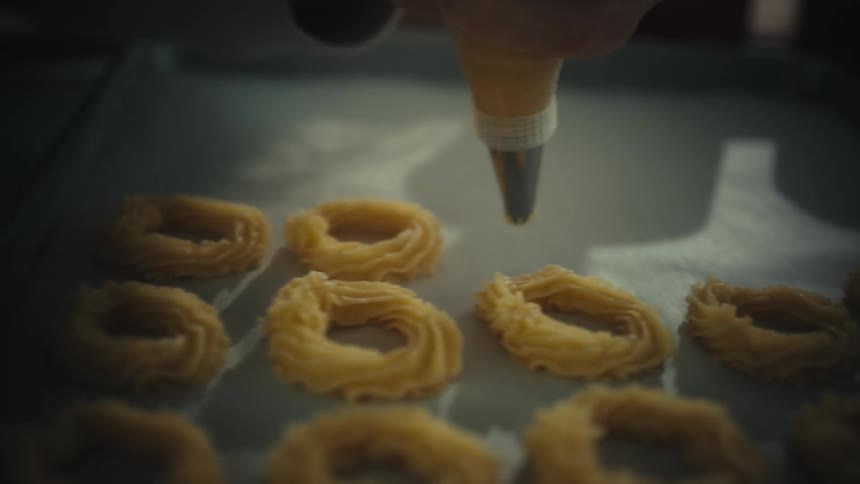 Piping nozzle forms dough rings on a tray