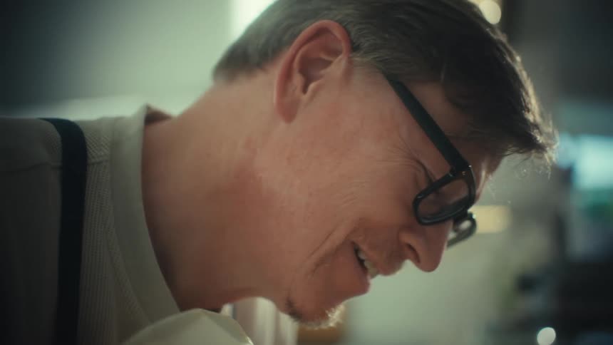 The man leans forward while smiling