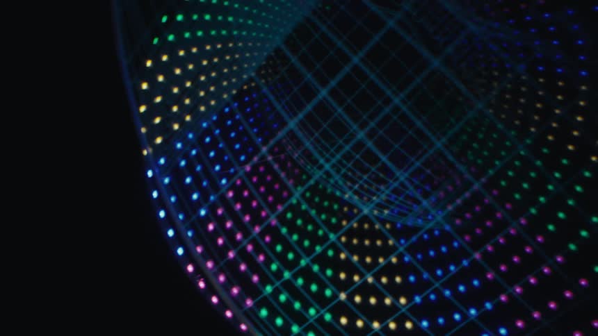 Glowing orbs of colored lights move across the darkness in a circular formation with the digitized outline of a football