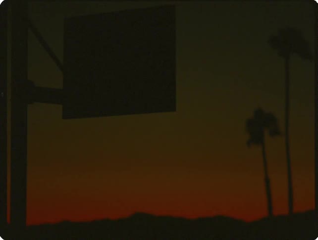 A coastal basketball court is captured in deep silhouette against a vibrant orange sunset with palm trees swaying as a brief flash of light illuminates the dramatic scene