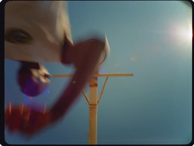 A basketball player moves under the hoop on a basketball court at sunset