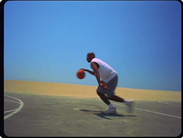 A man practices basketball dribbling and shooting on an outdoor court near a beach