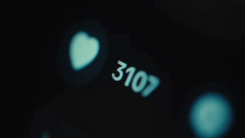 Macro shot of a digital heart icon and a numerical counter increasing rapidly on a dark screen