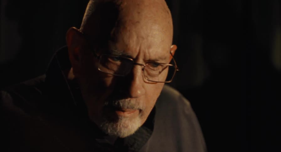 Close up of an older man drumming on a dark stage