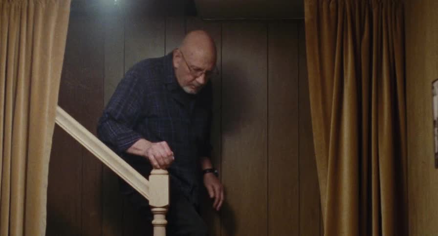 An elderly man walking down a staircase