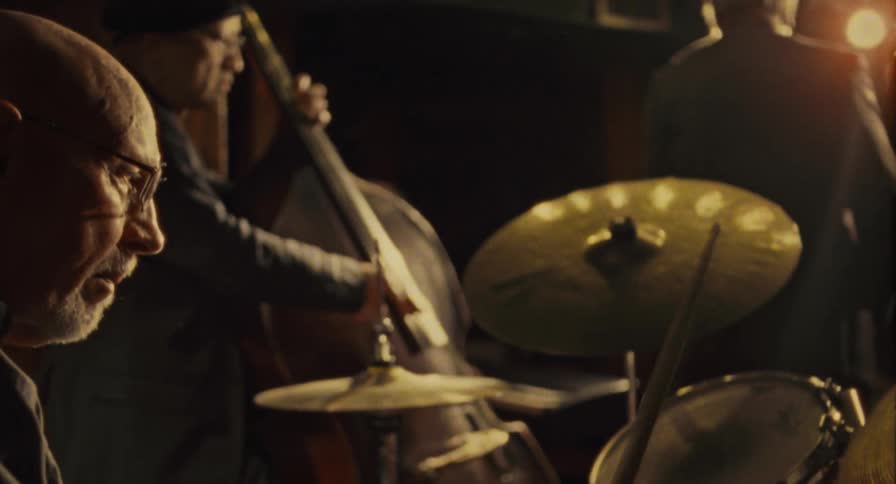 An older drummer plays in a band on stage