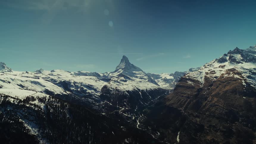 Snowcovered mountain peak surrounded by mountain ranges under a clear blue sky