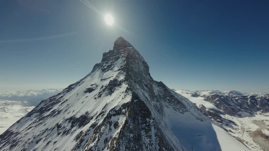 Snowcovered mountain peak rises under the sun in a blue sky
