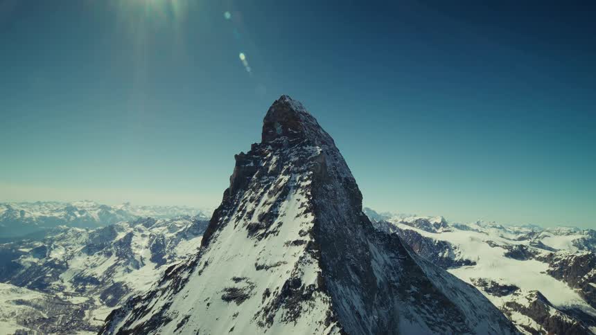 Aerial shot of a snow covered mountain peak under a clear blue sky