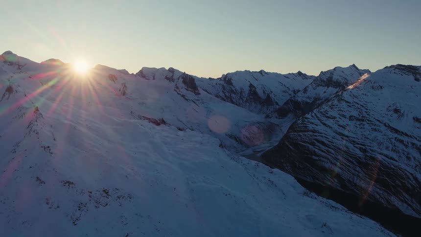 Snowcovered mountain ridge lit by rising sun