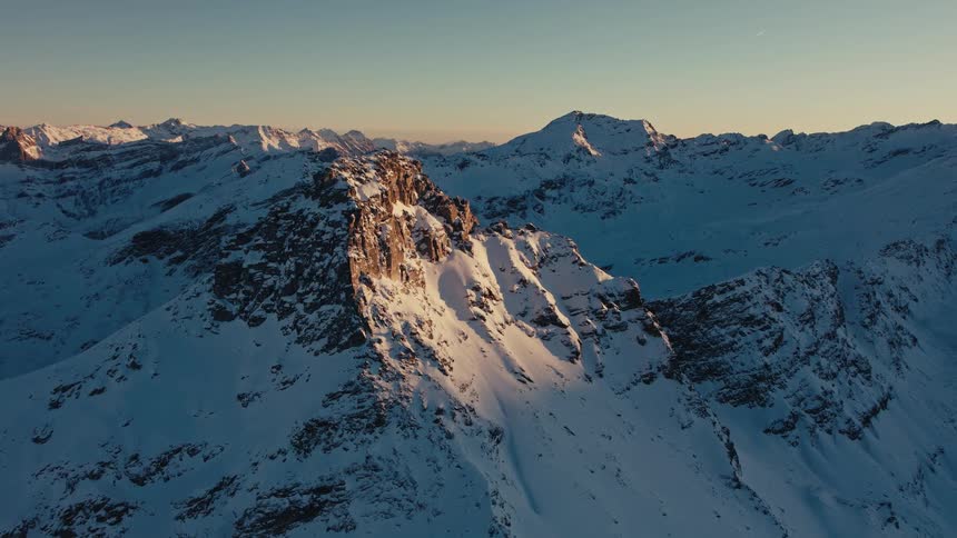 Snowcovered mountain range with rocky peaks illuminated by sunlight