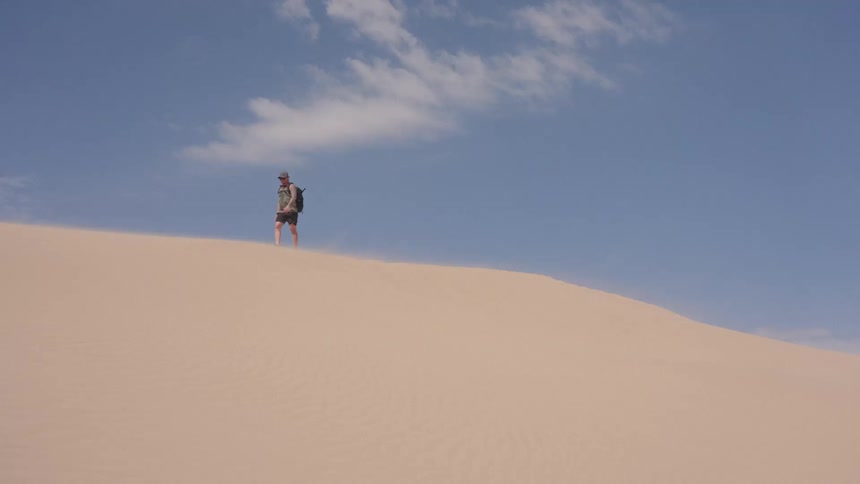 A person walking outdoors on a sand dune