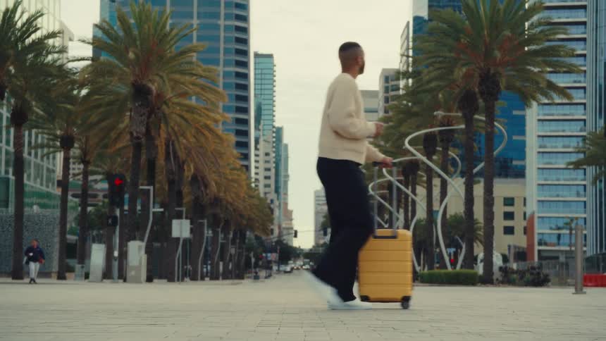 A man walking around in a city with a suitcase