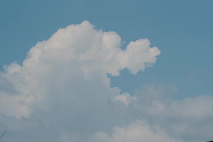 Cumulus clouds move across a blue sky