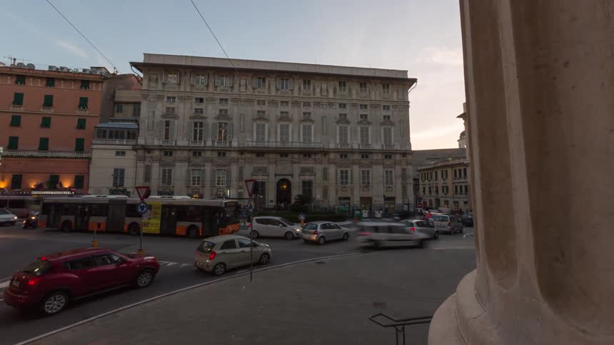 Buses and cars fill the city streets with many pedestrians walking on sidewalks in front of buildings