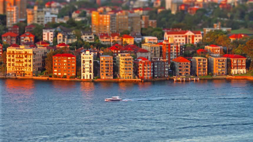 Watercraft leave wakes while moving through the water passing apartment buildings on the waterfront