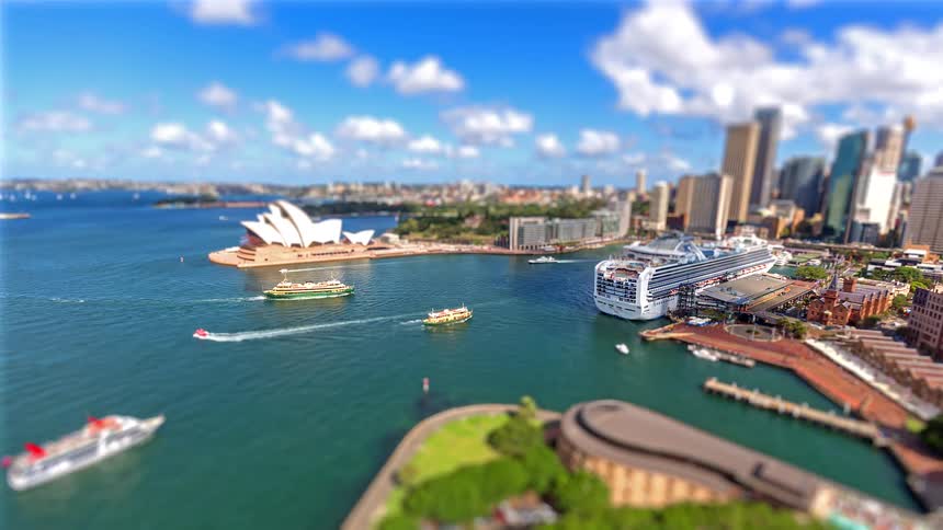 This tiltshift timelapse captures a toylike sydney harbour where miniature ferries and speedboats zip across turquoise waters toward the iconic opera housethe bright saturated colors and blurred foreground create a playful perspective