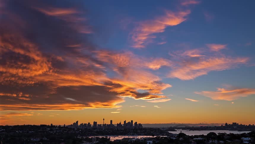 Urban skyline with bridge and bay under red clouds at dusk
