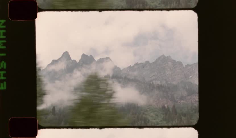Misty mountains rising above a forest landscape with clouds drifting through the peaks