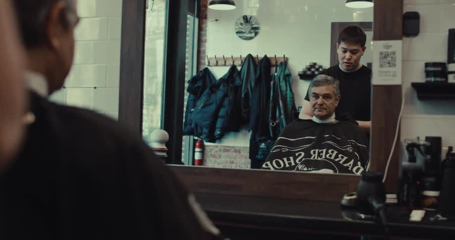 A man cutting another mans hair at a barbers shop