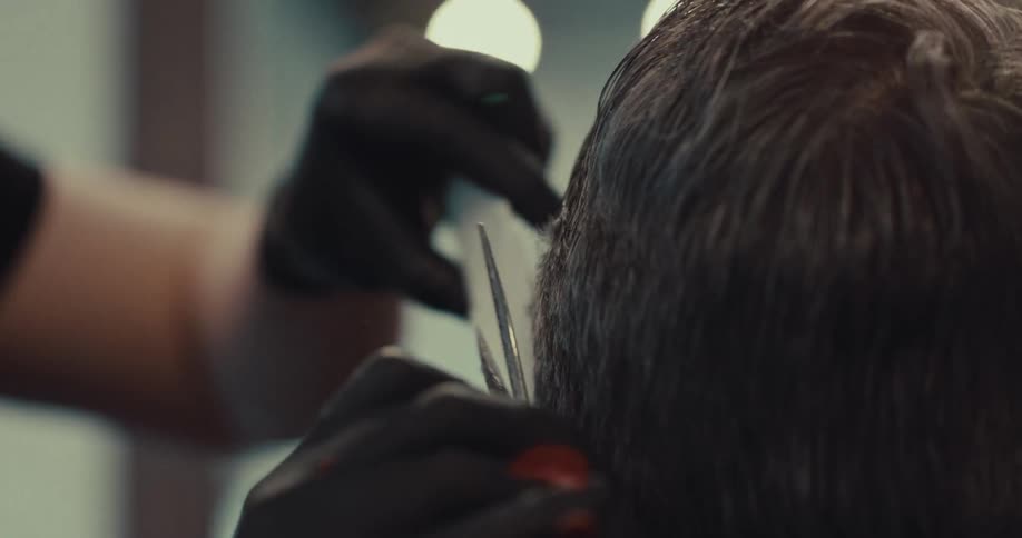 A closeup of a barber grooming a client with scissors in a barber shop