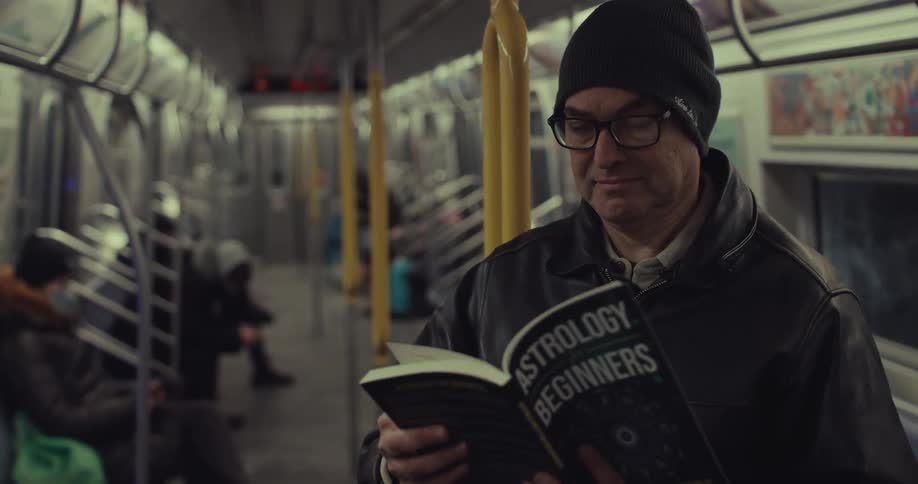 A man reading a book on a subway train