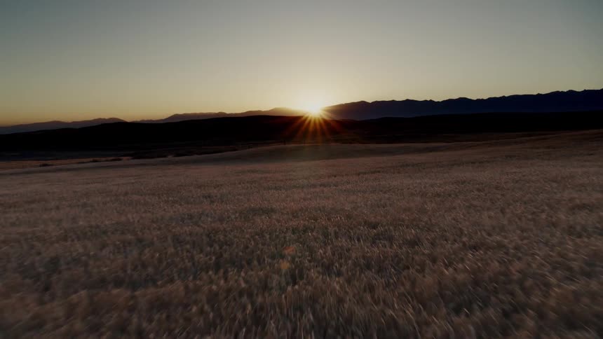 Aerial footage of the sun setting behind dark clouds over a field