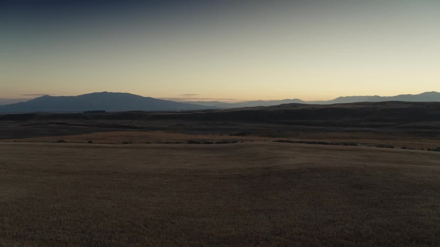 Land and hills across the rural landscape with mountains in the distance under a hazy sky