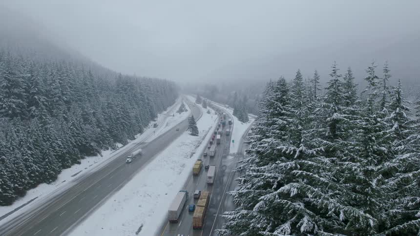 Reveal of stop and go traffic crawling up an icy mountain pass highway as a winter storm intensifies