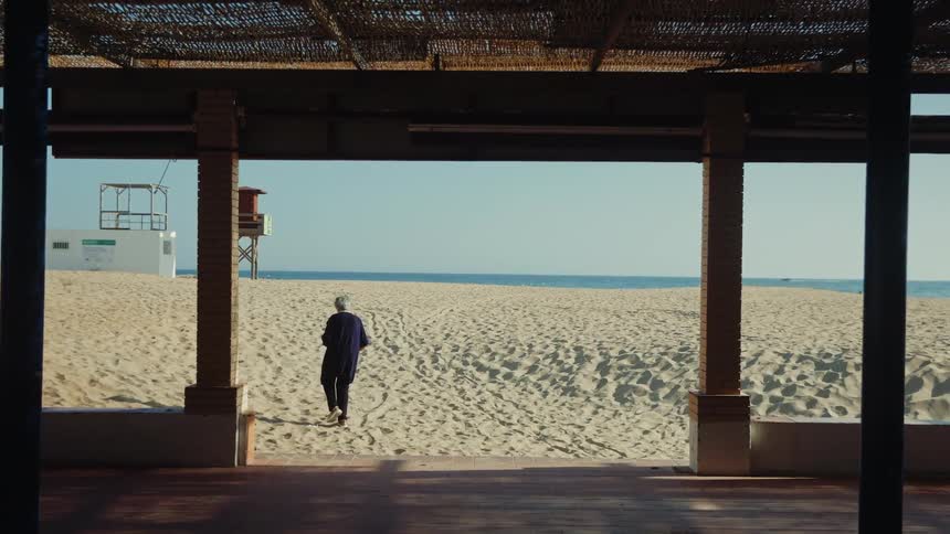 View from a porch of an elderly woman walking on the beach