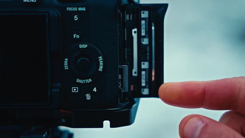 Man holds a memory card in his hand and places it inside a camera