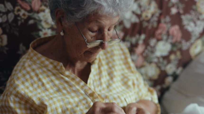 Elderly person crocheting a piece with colorful threads in their hands