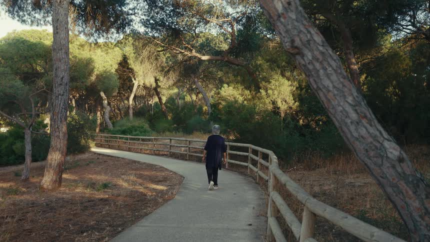 Woman walks on a sidewalk in a park surrounded by woodland