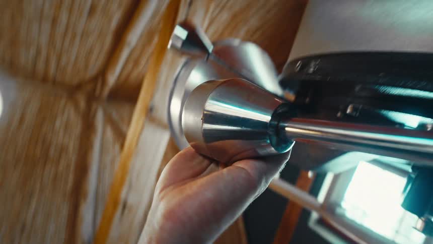 The video shows a closeup lowangle shot of a persons hand operating a piece of industrial machinery likely in a coffee roasting facilitythe first line of the video captures the hand gripping a polished metal handle or lever pulling it downward to