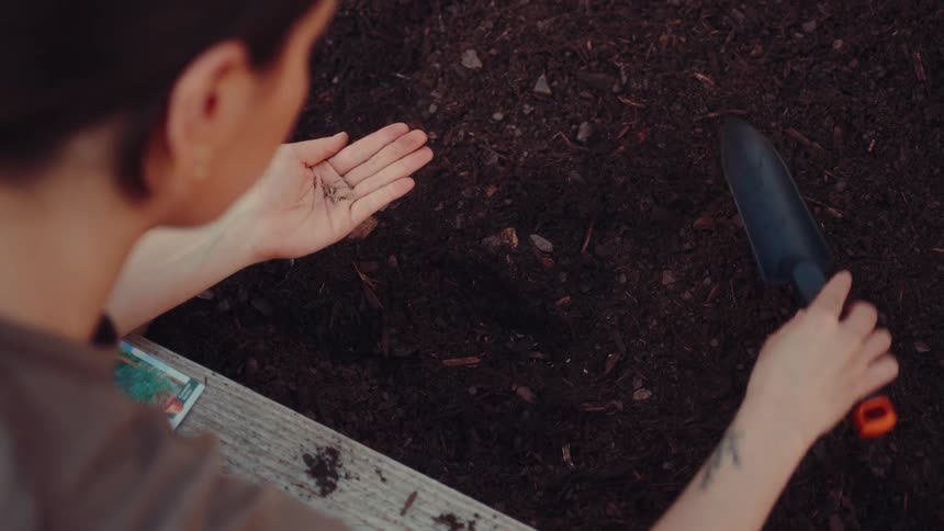 A woman planting seeds in a garden