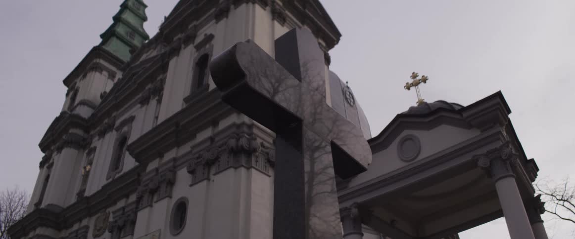 A church building with a large cross on the top and beside the building on a cloudy day