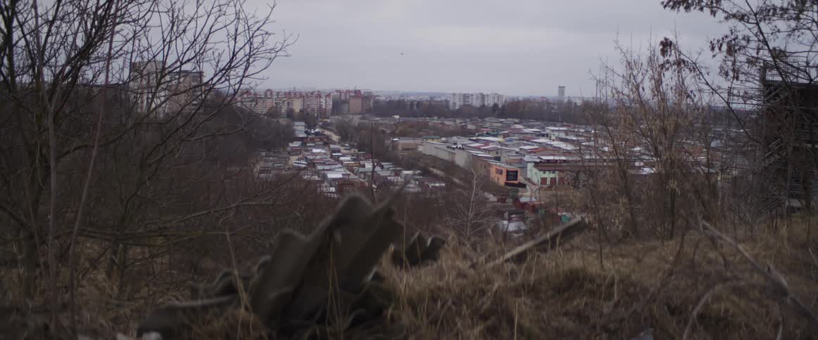 View of urban neighborhood with rows of houses and buildings in the distance under cloudy sky
