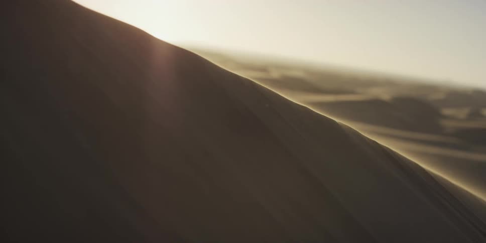 Some large sand dunes with wind blowing across them