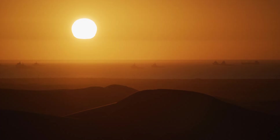 Sun above dunes forms silhouettes on the desert horizon