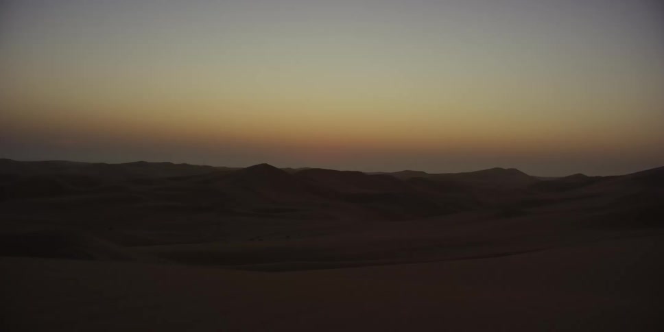 Sun sets behind dunes on the desert horizon