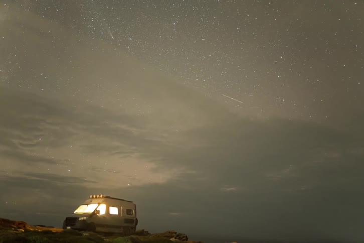 Person enters a small camper and bright light shines from its windows as night falls