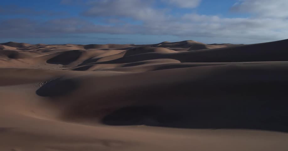 Dunes across the desert landscape under a cloudy sky