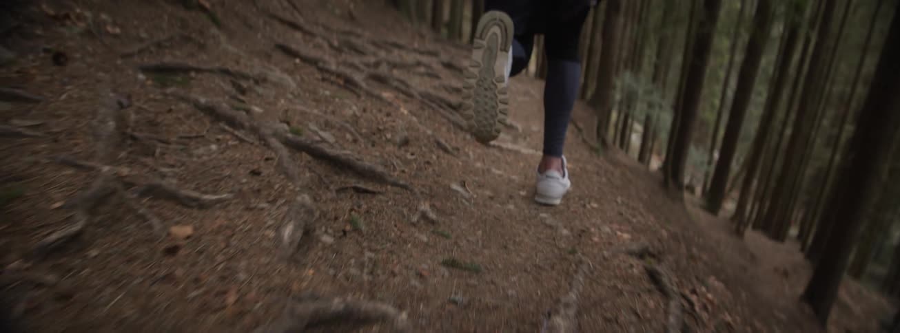Person running along dirt trail in forest