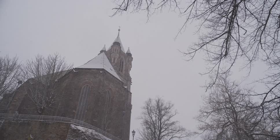 Stone church covered with snow surrounded by leafless trees